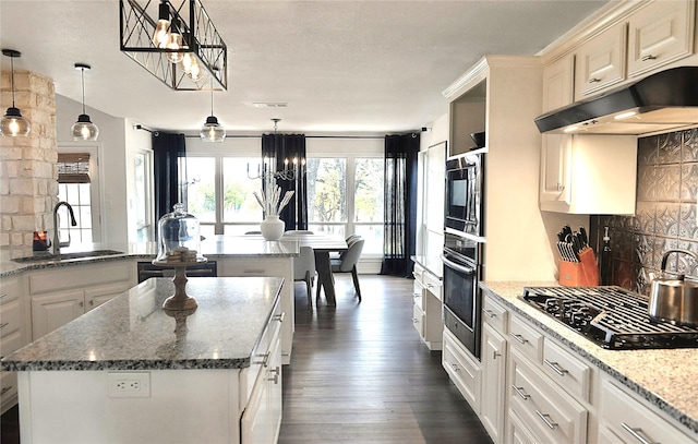 kitchen with a center island, oven, hanging light fixtures, and stainless steel gas stovetop