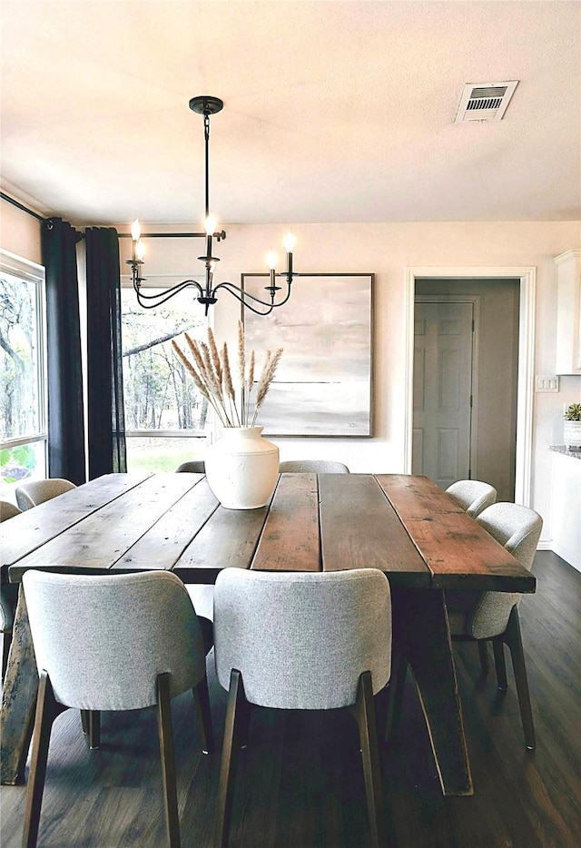 dining room with dark wood-type flooring and an inviting chandelier