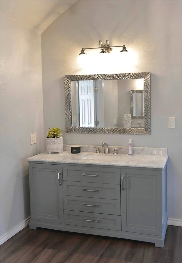 bathroom featuring hardwood / wood-style flooring, vanity, and vaulted ceiling