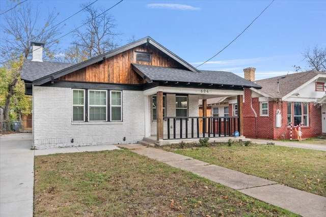 bungalow featuring covered porch and a front yard