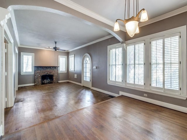 entrance foyer with crown molding, hardwood / wood-style floors, ceiling fan with notable chandelier, and a brick fireplace