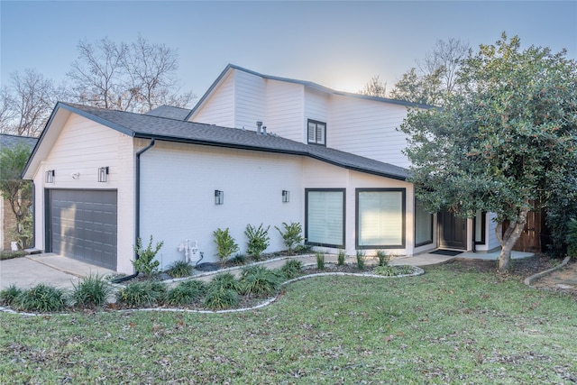 property exterior at dusk featuring a yard and a garage