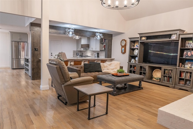 living room with a notable chandelier, light hardwood / wood-style floors, and lofted ceiling