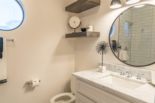 bathroom with vanity, toilet, and a tile shower