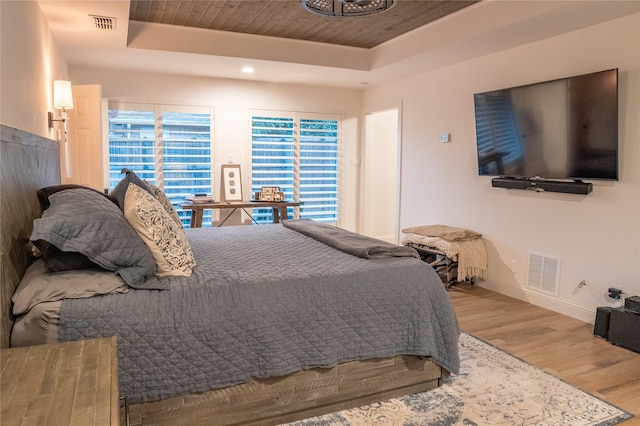 bedroom with wooden ceiling, wood-type flooring, and a tray ceiling