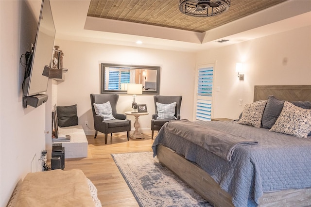 bedroom with light hardwood / wood-style floors, wooden ceiling, and a tray ceiling