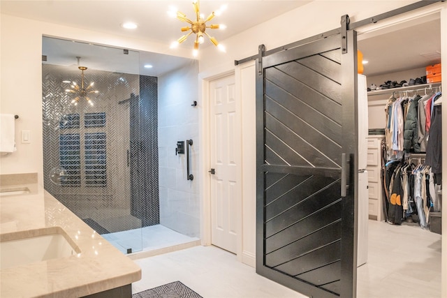 bathroom featuring a tile shower, vanity, and a notable chandelier