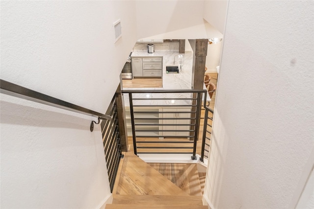 staircase with hardwood / wood-style floors and sink