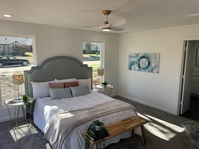 bedroom with dark colored carpet, multiple windows, and ceiling fan