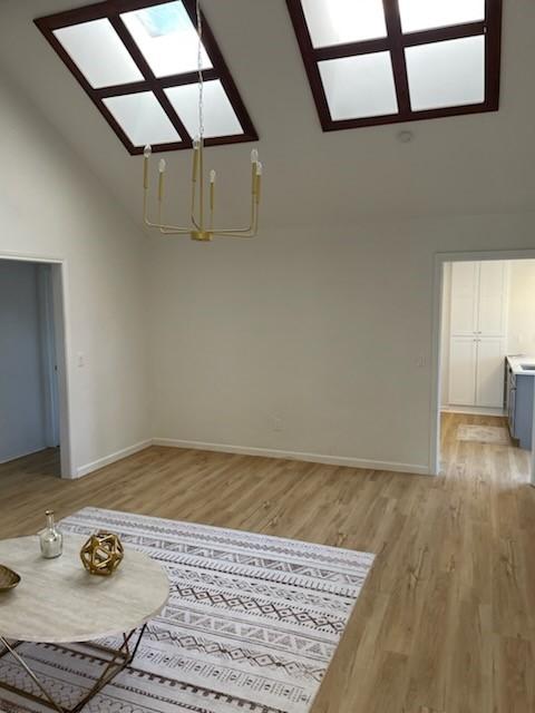 interior space with a chandelier, a towering ceiling, and light hardwood / wood-style floors