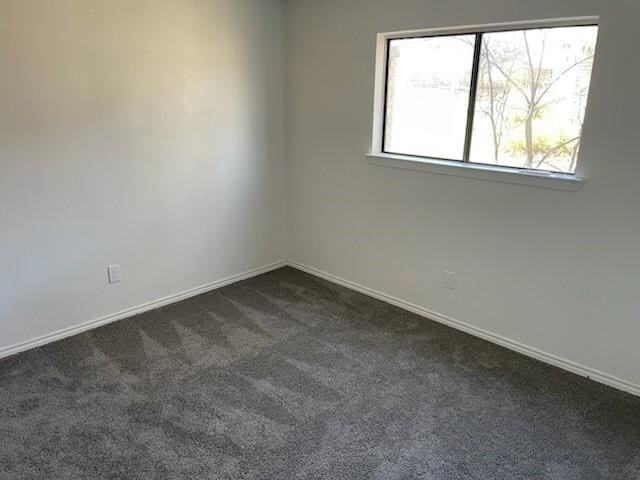 spare room with dark carpet