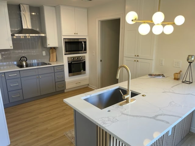 kitchen featuring appliances with stainless steel finishes, tasteful backsplash, sink, wall chimney range hood, and pendant lighting