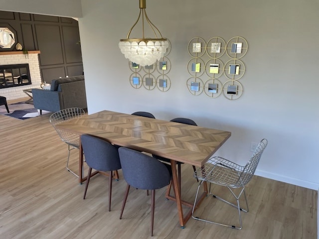 dining room featuring a notable chandelier, light wood-type flooring, and a fireplace