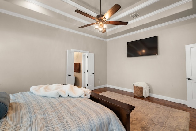 bedroom with hardwood / wood-style flooring, ceiling fan, crown molding, and a tray ceiling