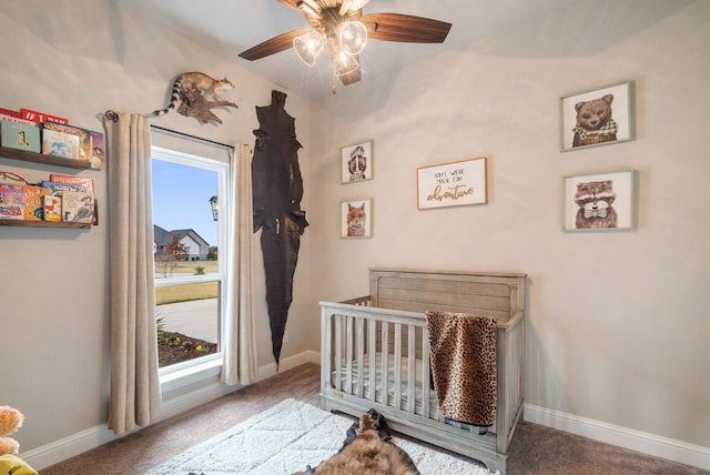 carpeted bedroom featuring a nursery area and ceiling fan