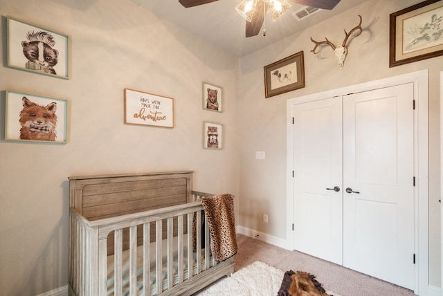 carpeted bedroom featuring a crib, a closet, and ceiling fan