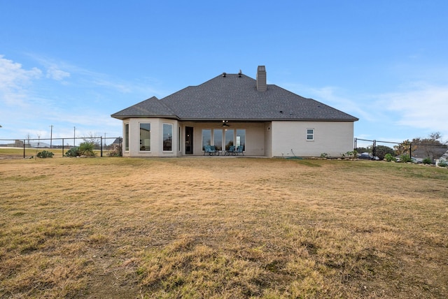 back of property featuring a yard and ceiling fan