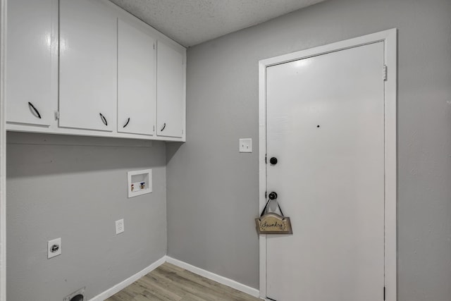 laundry area with cabinets, a textured ceiling, hookup for a washing machine, electric dryer hookup, and light hardwood / wood-style floors