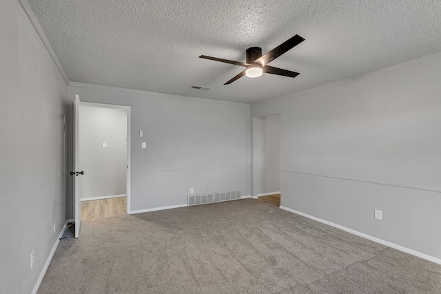 empty room with crown molding, ceiling fan, carpet floors, and a textured ceiling