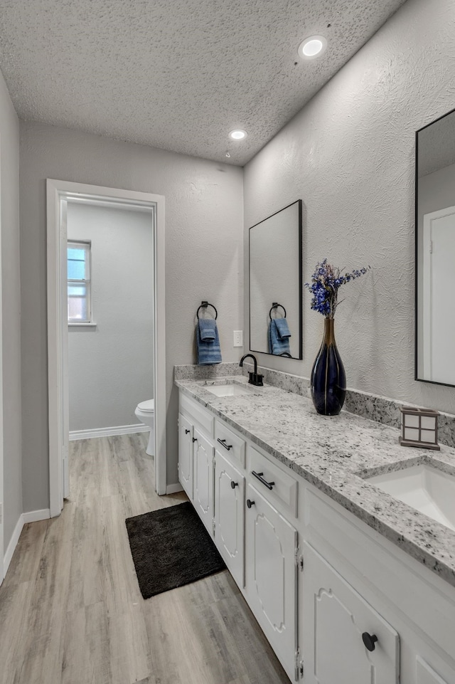 bathroom with hardwood / wood-style flooring, vanity, a textured ceiling, and toilet