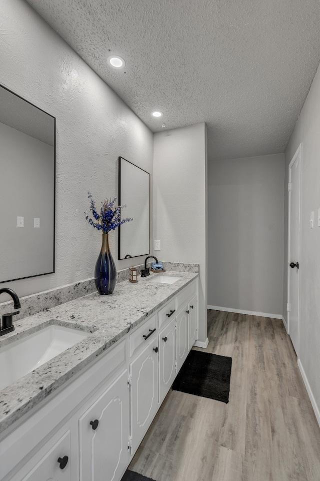 bathroom with hardwood / wood-style flooring, vanity, and a textured ceiling