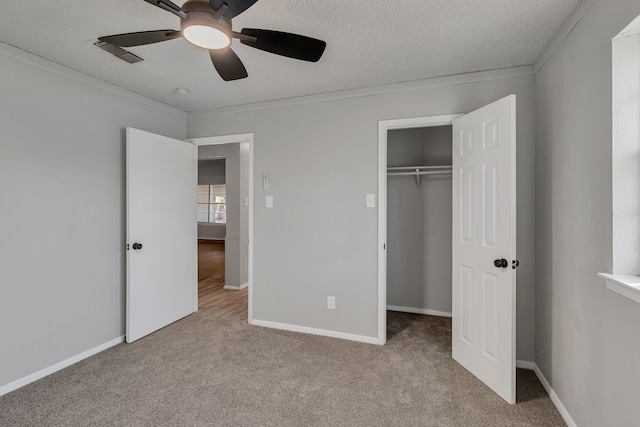 unfurnished bedroom with light carpet, ceiling fan, a closet, and a textured ceiling