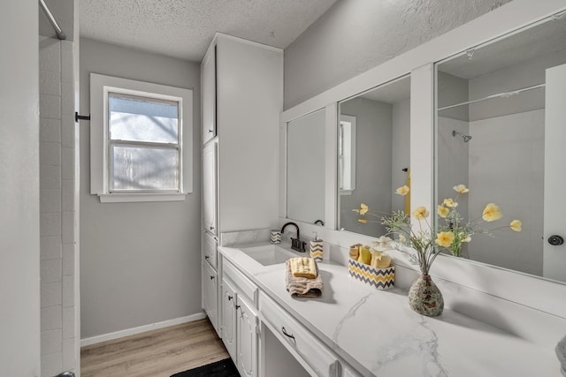 bathroom featuring hardwood / wood-style flooring, tiled shower, vanity, and a textured ceiling