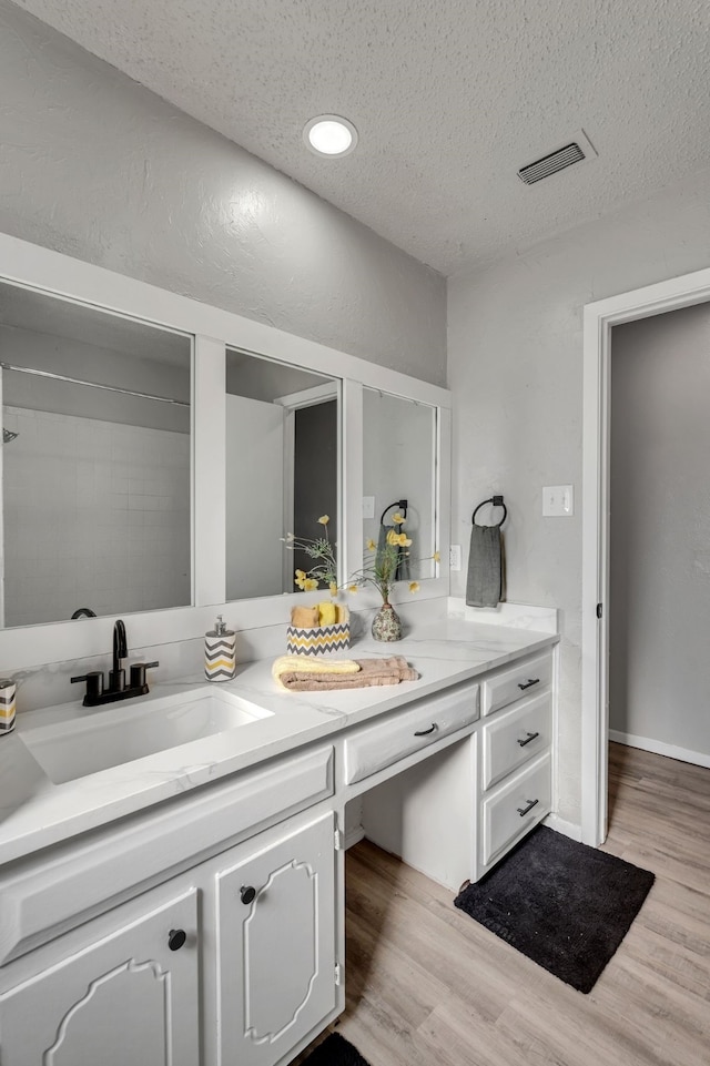 bathroom featuring vanity, wood-type flooring, and a textured ceiling