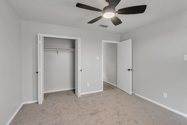 unfurnished bedroom featuring ceiling fan, light carpet, a textured ceiling, and a closet