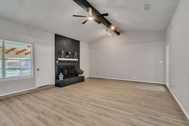 unfurnished living room featuring a fireplace, a textured ceiling, light hardwood / wood-style flooring, and vaulted ceiling with beams