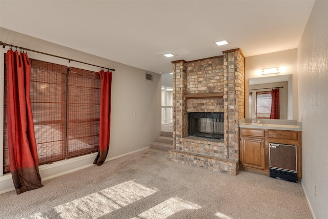 unfurnished living room with light carpet and a fireplace