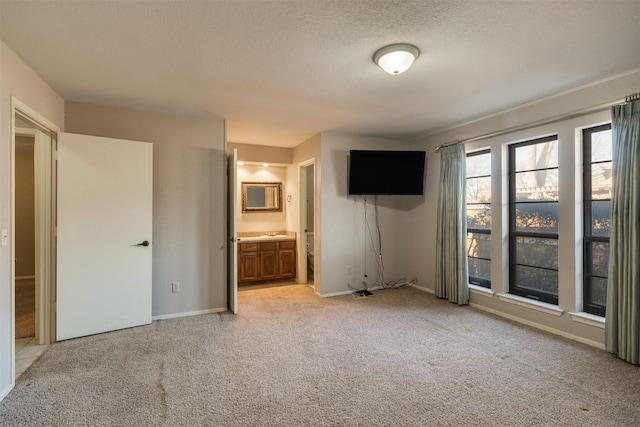 unfurnished bedroom with light colored carpet, connected bathroom, and a textured ceiling