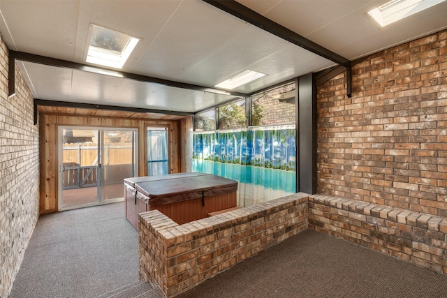 rec room featuring beamed ceiling, brick wall, light colored carpet, and a skylight