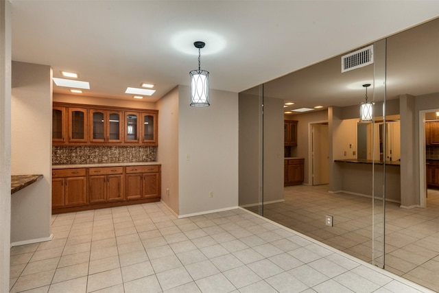 kitchen featuring decorative light fixtures, a skylight, decorative backsplash, and light tile patterned flooring