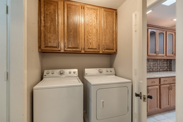 laundry room with light tile patterned floors, washer and clothes dryer, and cabinets