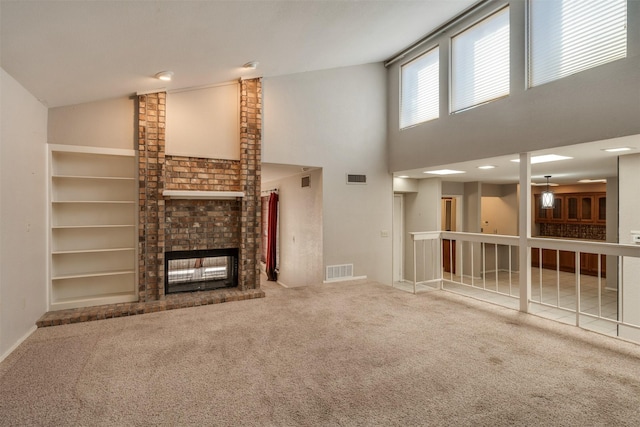 unfurnished living room with high vaulted ceiling, carpet, and a brick fireplace