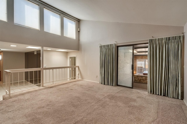 unfurnished room featuring plenty of natural light, high vaulted ceiling, and carpet