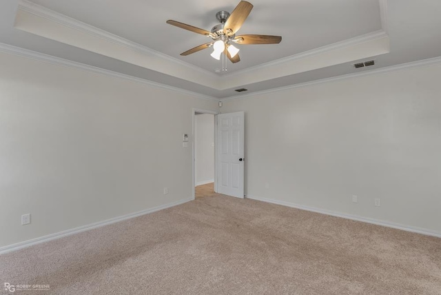 carpeted spare room featuring crown molding, a tray ceiling, and ceiling fan