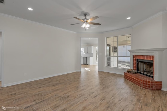 unfurnished living room featuring a brick fireplace, crown molding, light hardwood / wood-style flooring, and ceiling fan