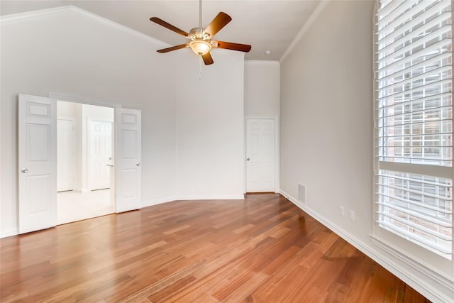 unfurnished bedroom with crown molding, ceiling fan, light hardwood / wood-style floors, and a high ceiling