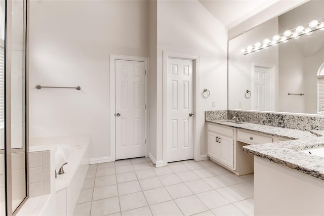 bathroom with tile patterned flooring, vanity, lofted ceiling, and a bath