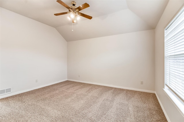 carpeted empty room with lofted ceiling, plenty of natural light, and ceiling fan