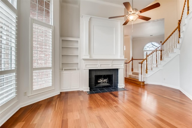 unfurnished living room featuring ceiling fan, light hardwood / wood-style floors, and a tile fireplace