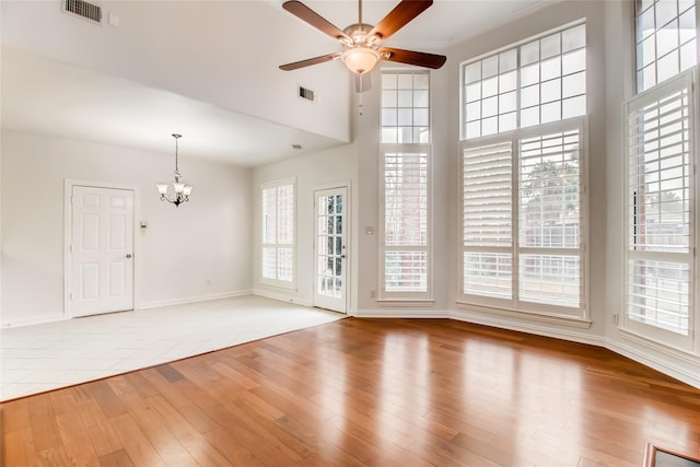 unfurnished living room featuring ceiling fan with notable chandelier and light hardwood / wood-style flooring