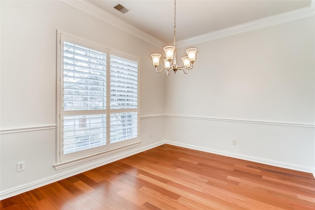 unfurnished room featuring a notable chandelier, ornamental molding, and hardwood / wood-style floors