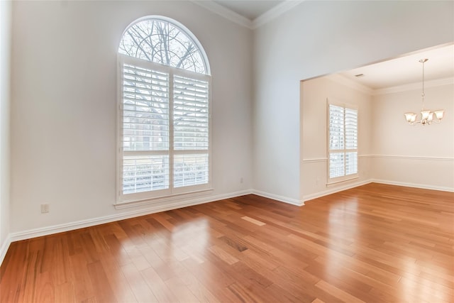 empty room featuring an inviting chandelier, a healthy amount of sunlight, and hardwood / wood-style flooring