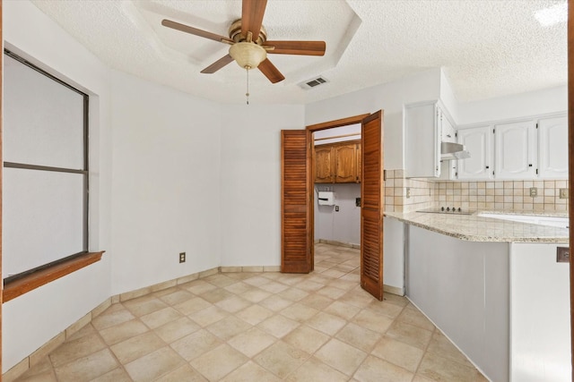 kitchen featuring ceiling fan, light stone counters, black electric cooktop, decorative backsplash, and white cabinets