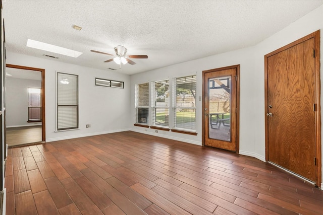 unfurnished room with ceiling fan, dark hardwood / wood-style floors, and a skylight