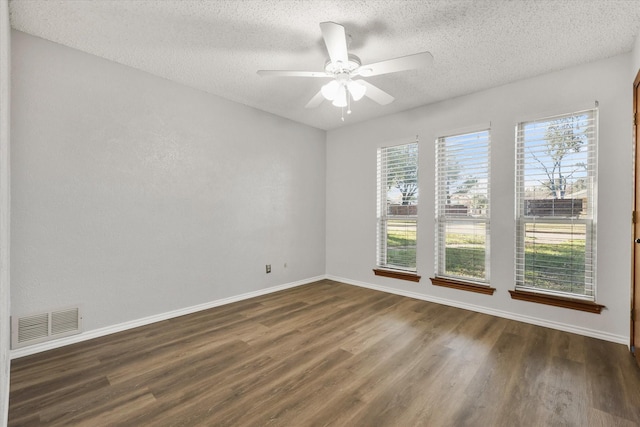 spare room featuring a textured ceiling, a wealth of natural light, ceiling fan, and dark hardwood / wood-style floors