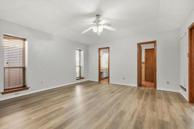 unfurnished bedroom with connected bathroom, ceiling fan, a textured ceiling, and light wood-type flooring